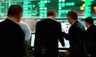 Create an image depicting a futuristic stock exchange floor bustling with activity, where digital screens prominently display bitcoin symbols and charts. Traders are animatedly discussing and analyzin